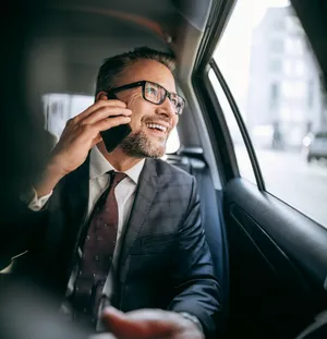 Professional chauffeur waiting by luxury car for hourly service